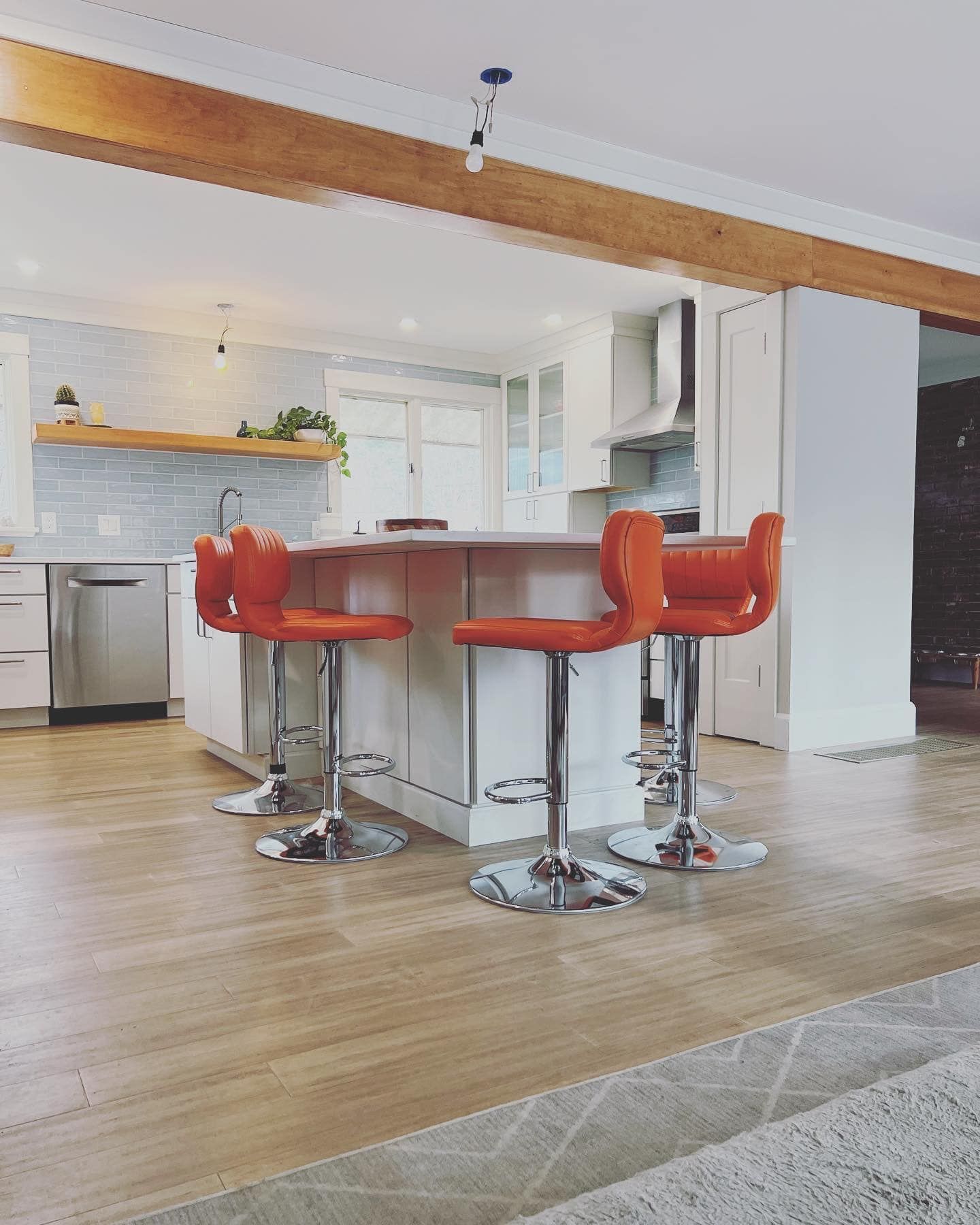 A kitchen with a large island and two orange bar stools.