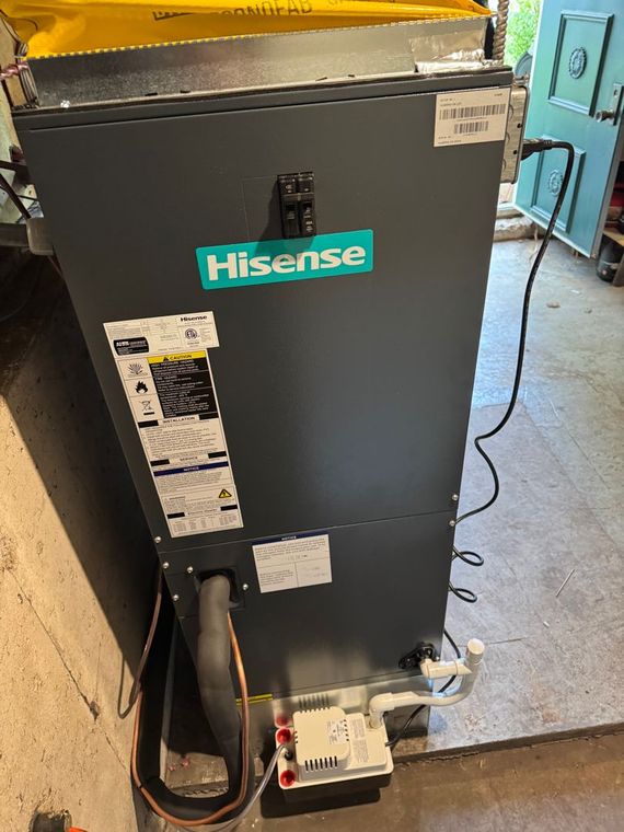 Hisense HVAC unit, gray, with teal logo, near a wall and door.