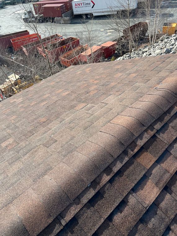 Close-up of a layered roof, with a background of shipping containers and industrial setting.