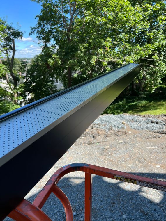 Black metal structure with perforated top, outdoors.
