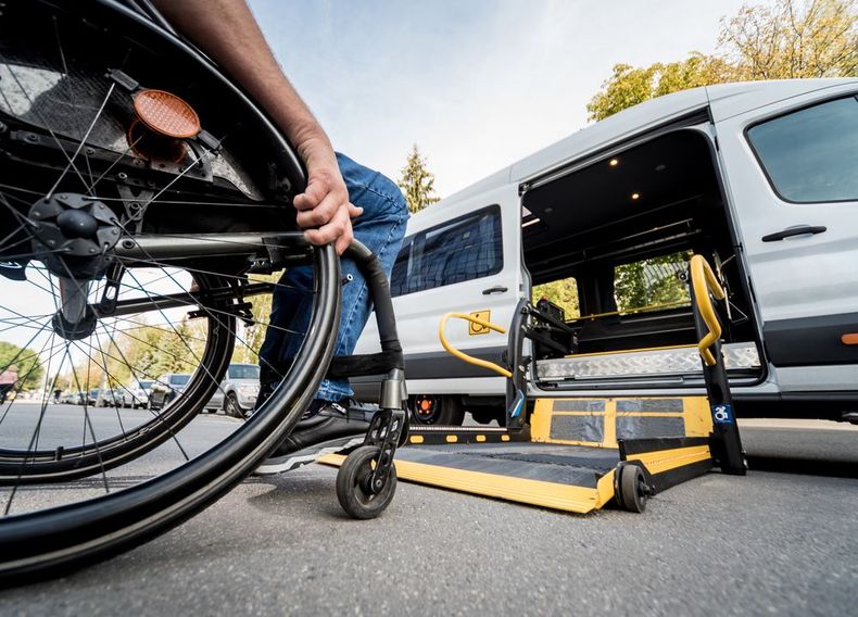 Wheelchair being loaded onto a van via a rear lift ramp on a city street.