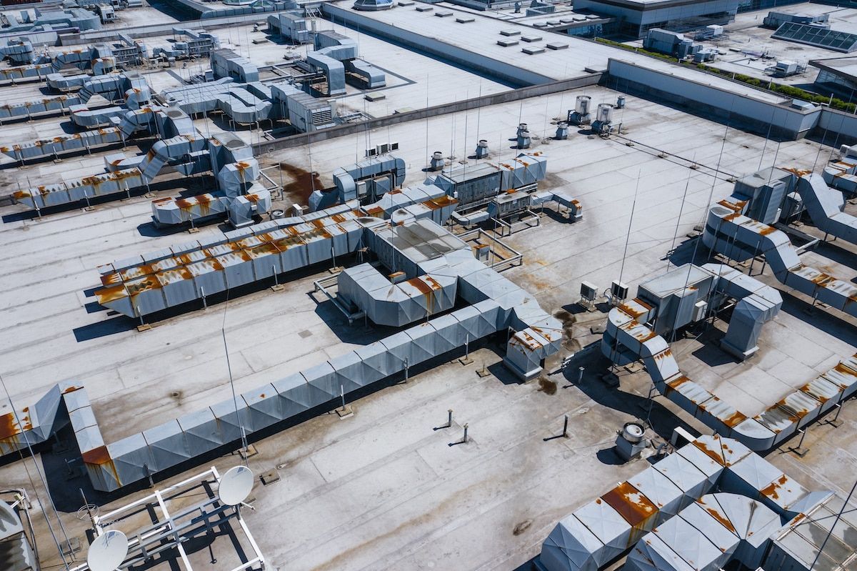 An aerial view of a large building with a lot of pipes on the roof.