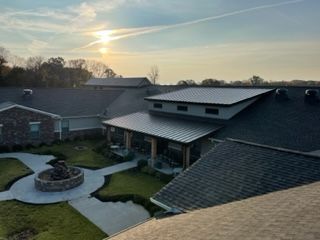 An aerial view of a large house with a roof that is covered in solar panels.