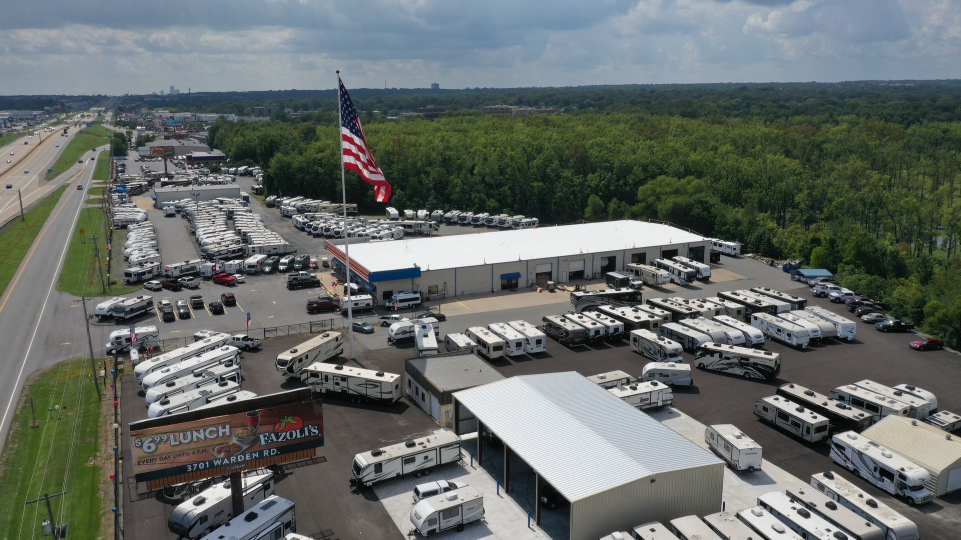 An aerial view of a rv park with a large american flag in the background.
