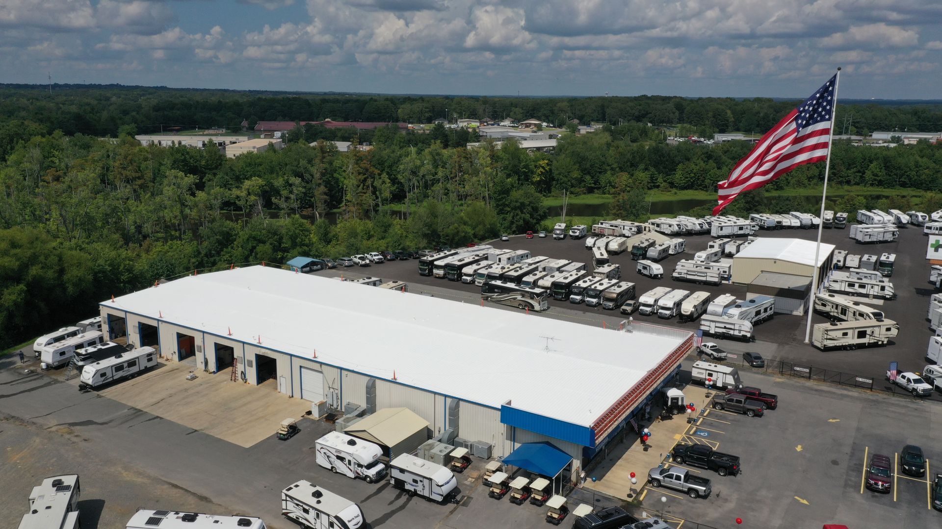 An aerial view of a large parking lot with a large american flag flying in the middle.
