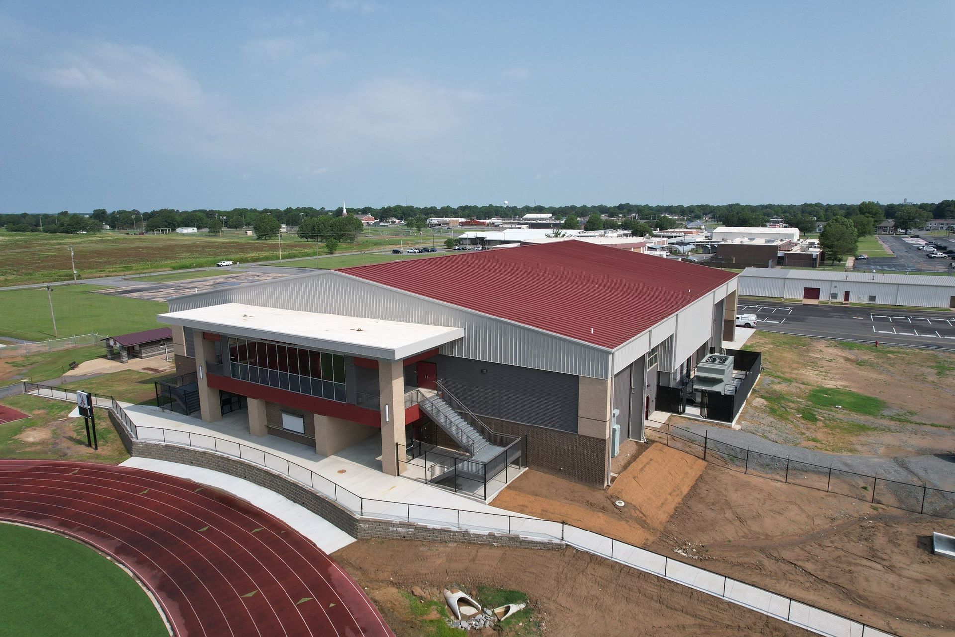 An aerial view of a building with a red roof and a track in front of it.