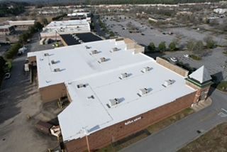 An aerial view of a large building with a white roof.