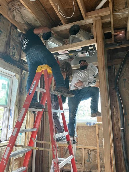 Two men are standing on ladders in a room.