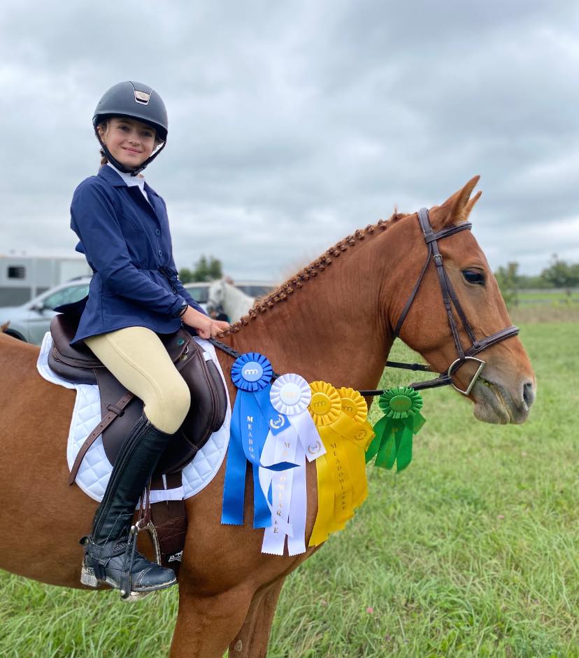 Young rider on horse with winning ribbons at show
