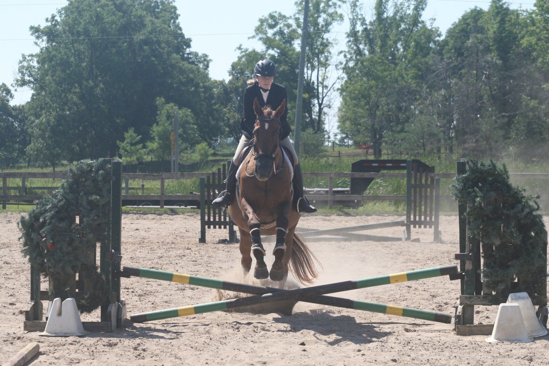 Young rider on horse jumping a cross rail in sand ring