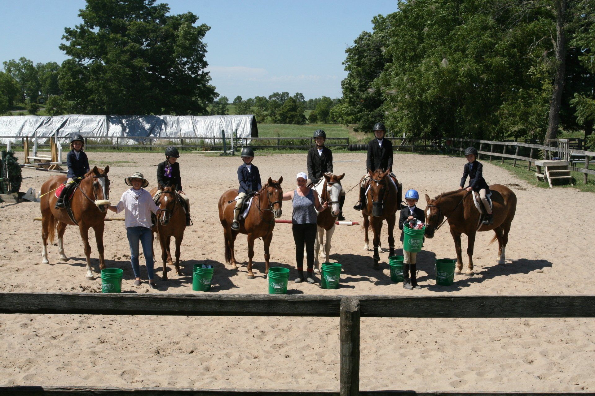 Group of kids with horses in sand ring for show prep camp