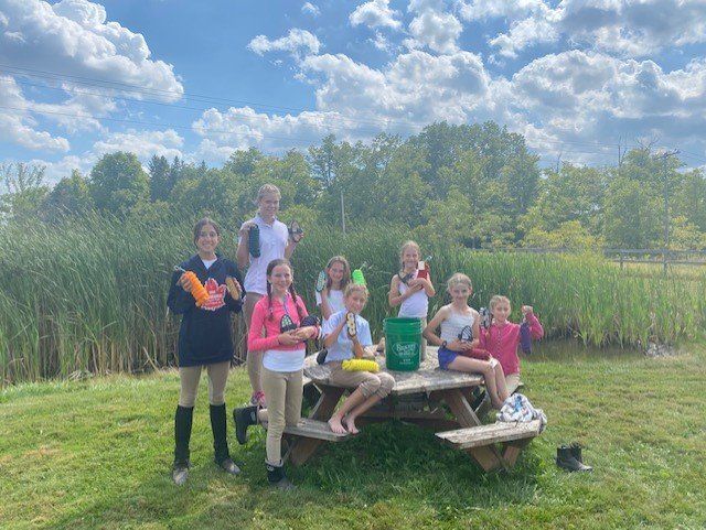 Group of young riders sitting at a picnic table at equestrian facility