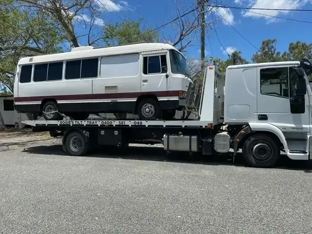 White Bus on A Flatbed Tow Truck on A Paved Road — Sundance Auto & Machinery Pty Ltd In Midge Point, QLD