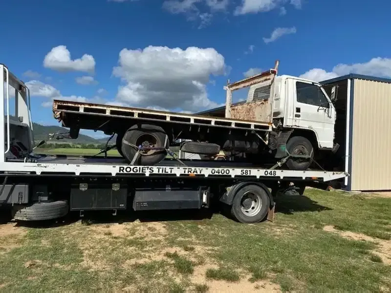 White Flatbed Truck Carrying a Rusty Work Truck on A Sunny Day — Sundance Auto & Machinery Pty Ltd In Midge Point, QLD 