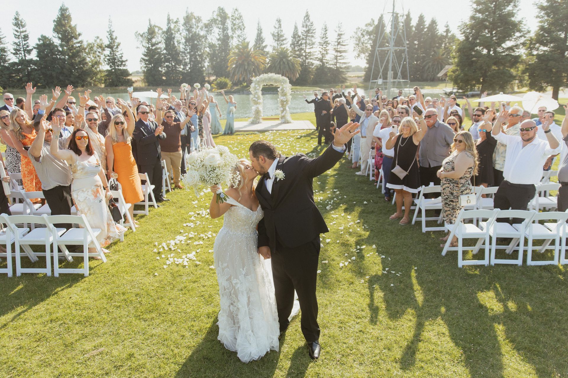 A bride and groom are kissing in front of a crowd of people at their wedding ceremony.