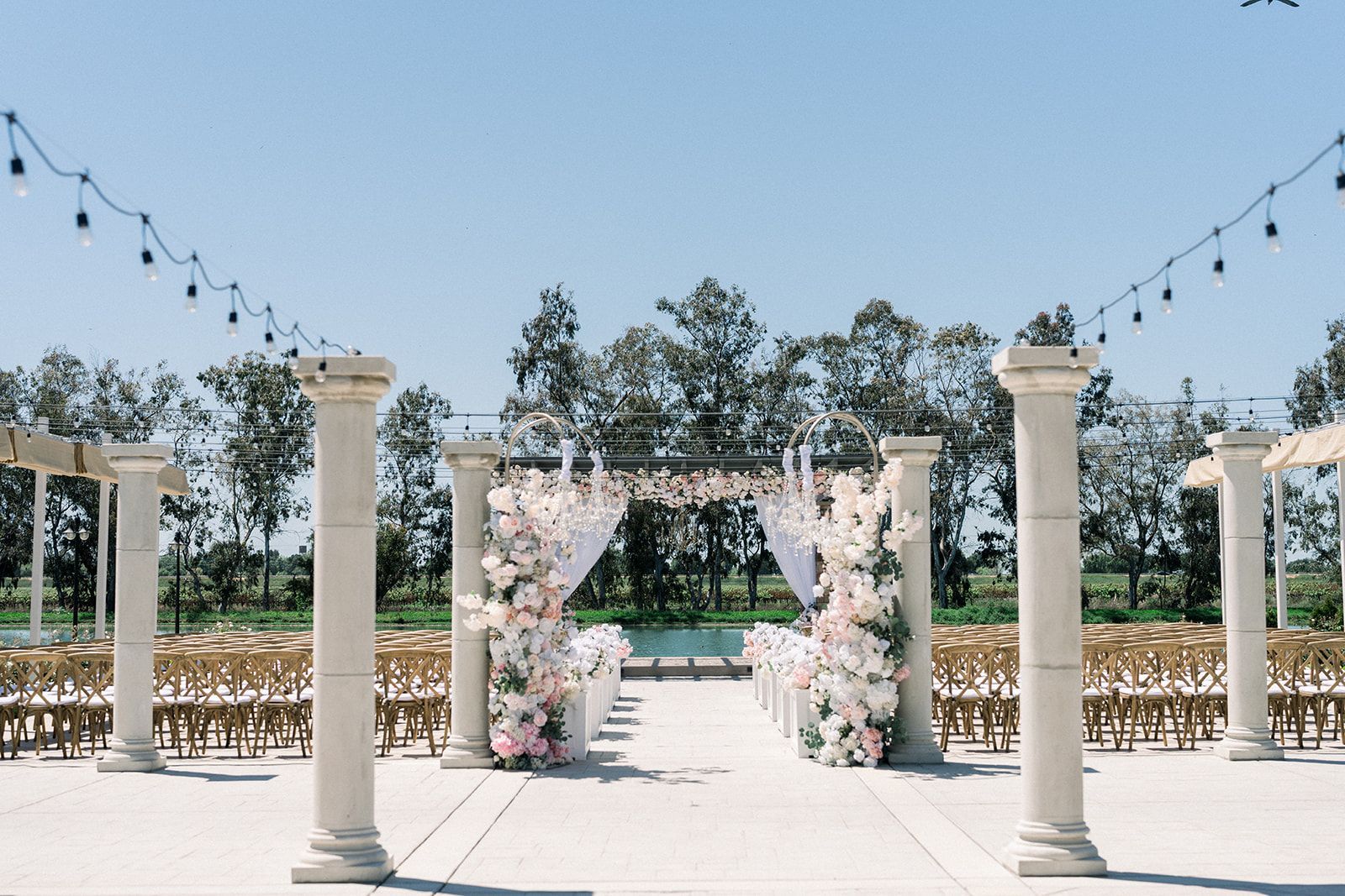 A wedding ceremony is being held in a courtyard with columns and chairs.