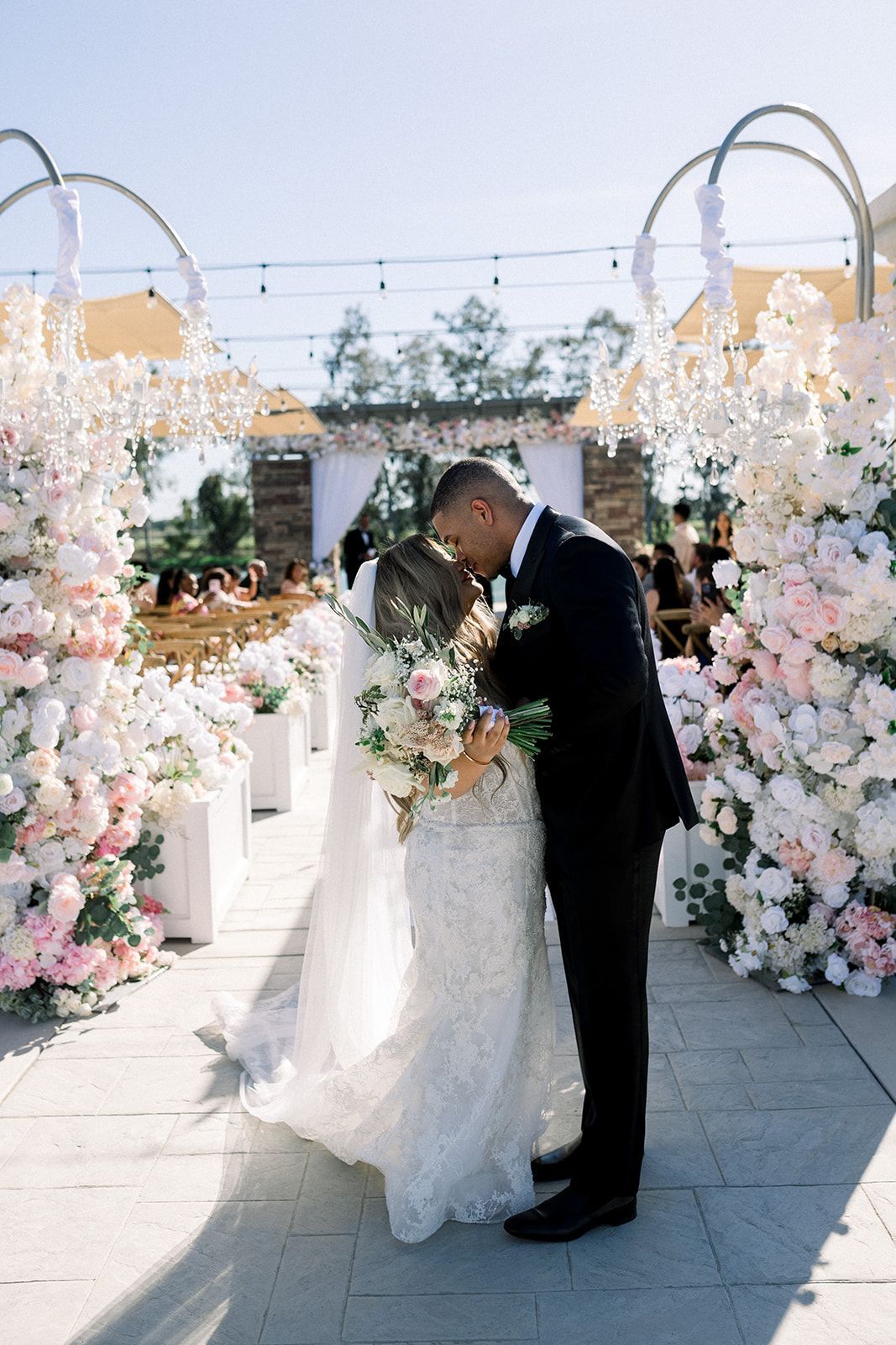 A bride and groom are kissing at their wedding ceremony.