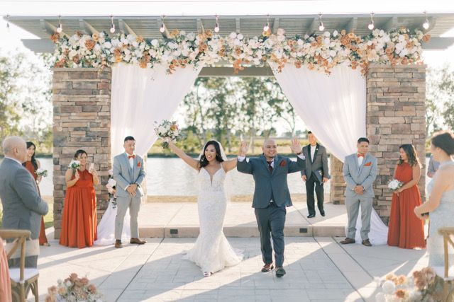 happy newlywed couple leaving the alter with hands up thanking invited wedding ceremony guests