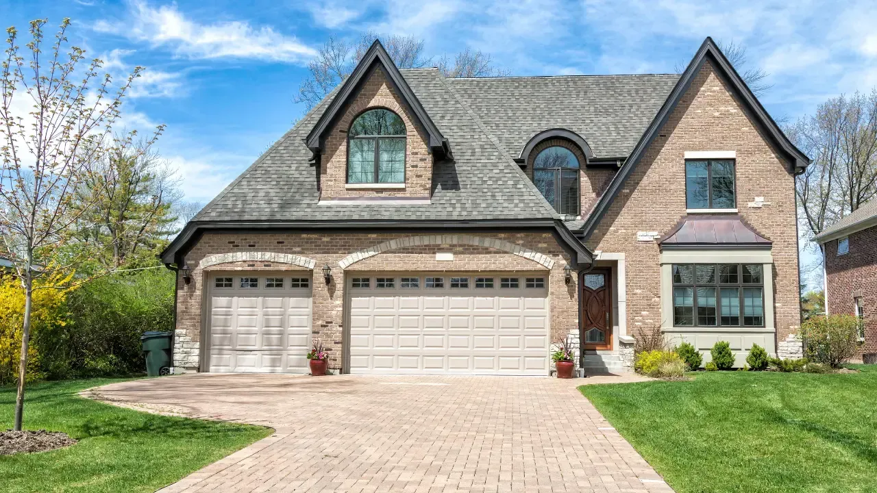A large brick house with two garage doors and a brick driveway. whittier