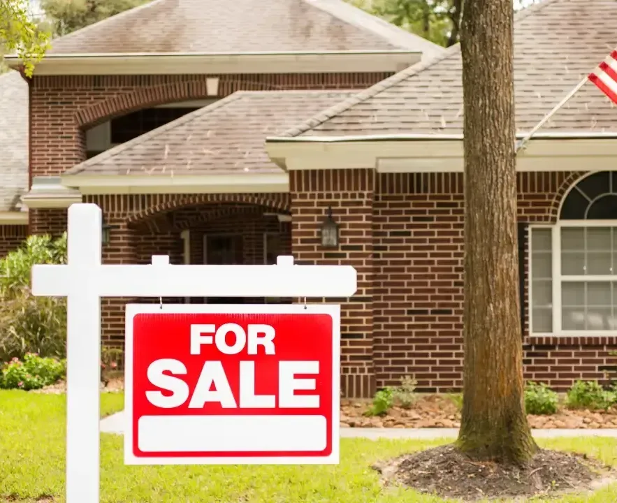 A for sale sign in front of a brick house