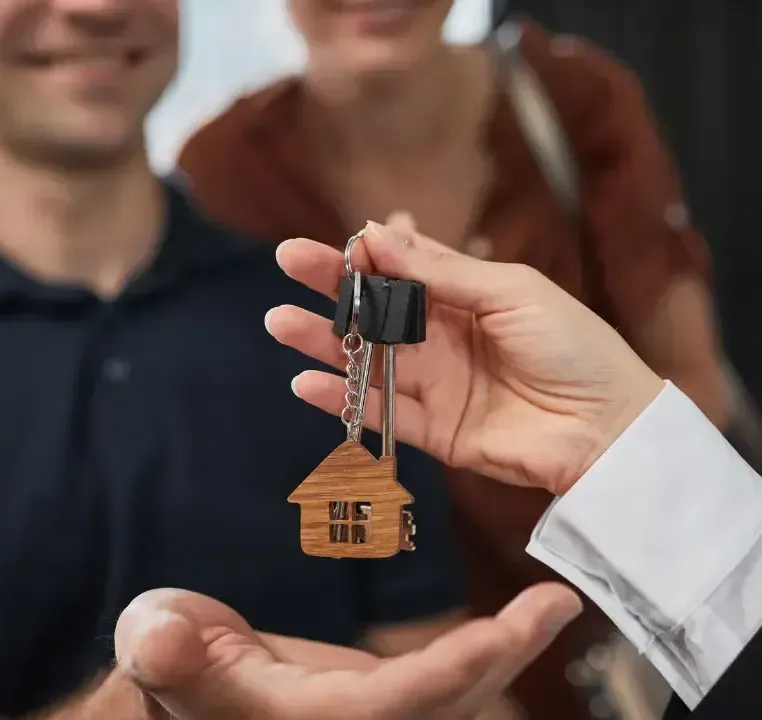 A man is handing a woman a set of house keys