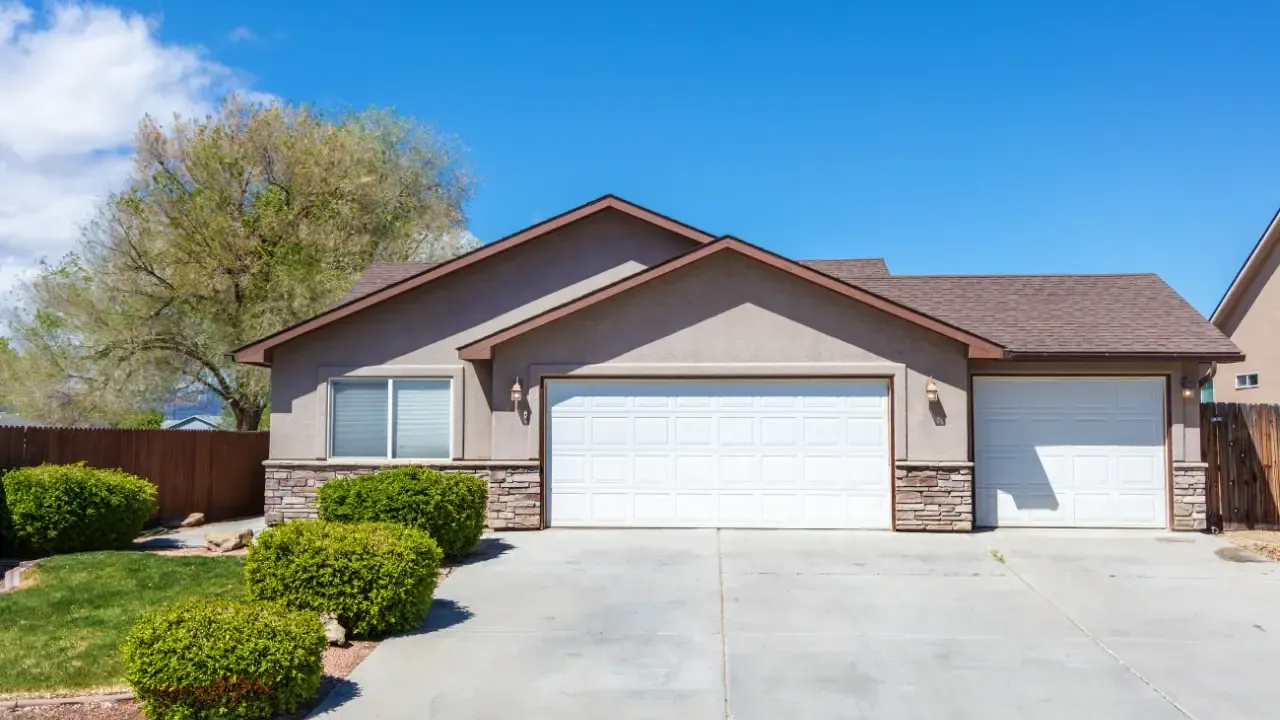 A house with two garage doors and a concrete driveway.