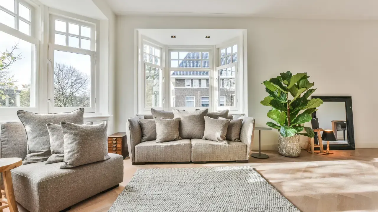 A living room with a couch , chair , rug and a large window.