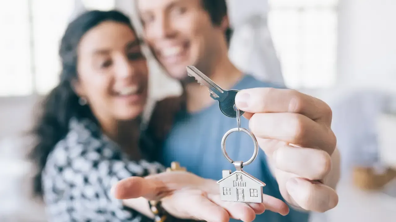 A man and a woman are holding keys to their new home.