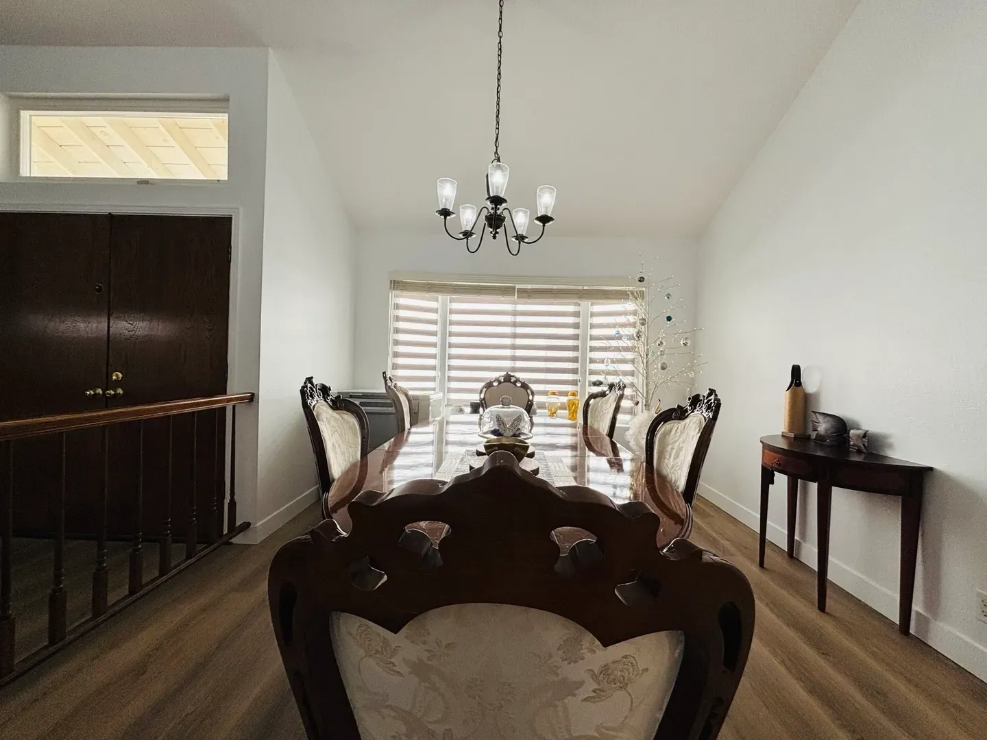 A dining room with a long table and chairs and a chandelier.