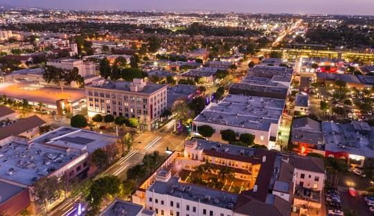 An aerial view of a city at night with lots of buildings and trees.