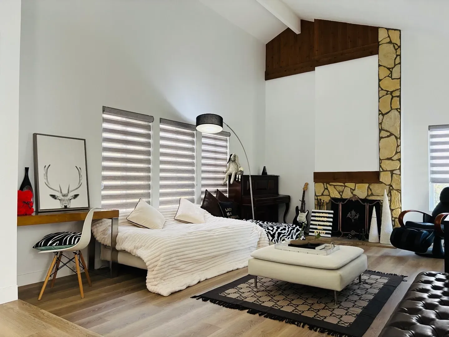 A living room with a bed , ottoman , chair and fireplace.
