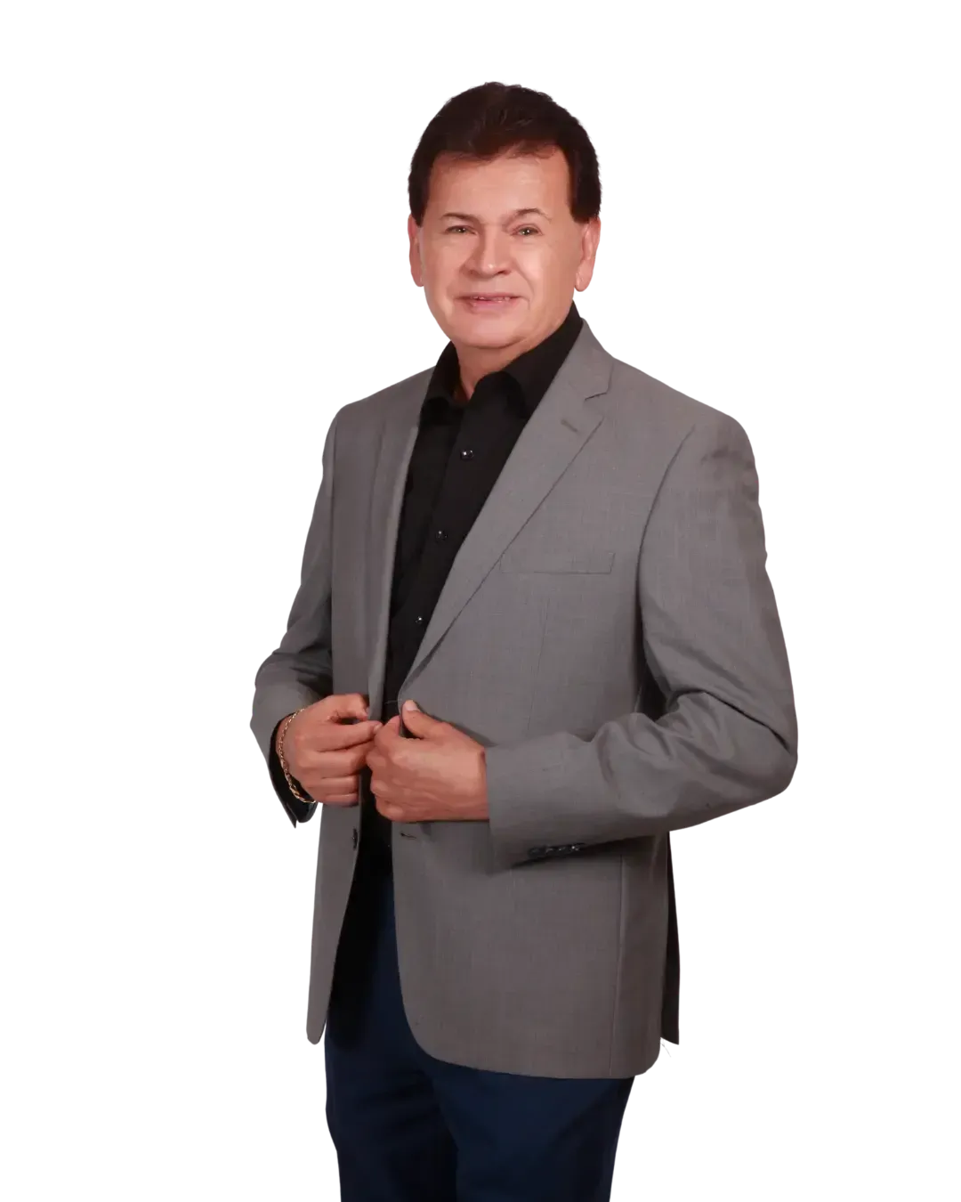 A man in a grey jacket and black shirt is standing in front of a white background. Samual Gonzalez