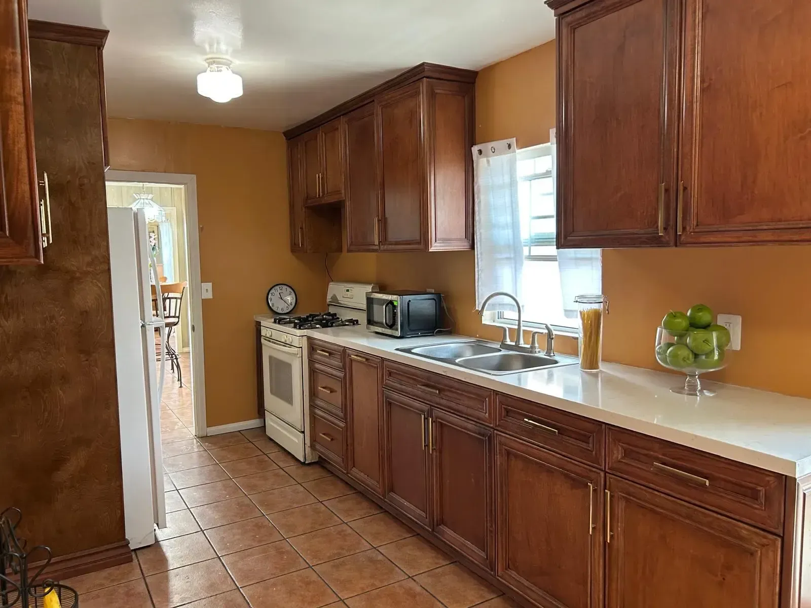 A kitchen with wooden cabinets , a stove , sink , and microwave.