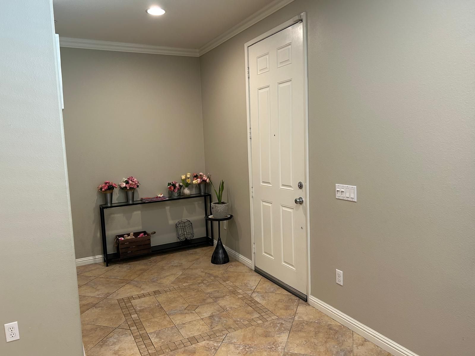 A hallway with a door and a table with flowers on it.