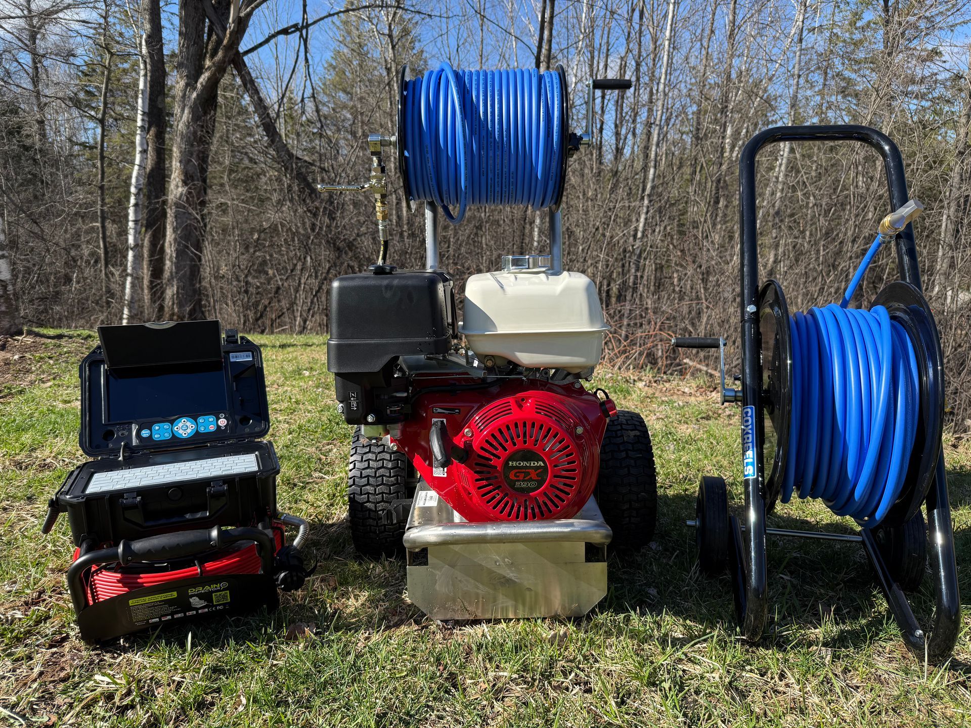 Three pressure washers are sitting on top of a lush green field.