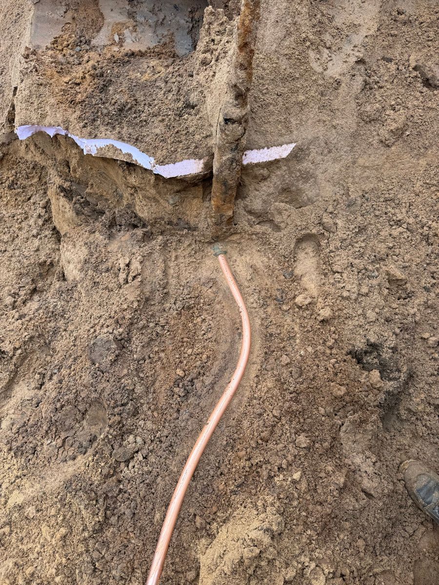 A close up of a copper wire in the dirt.