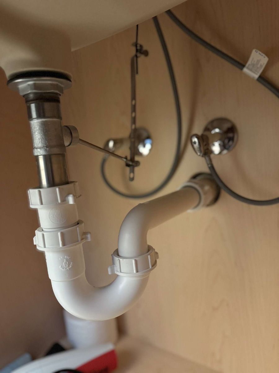 A white pipe under a sink with a chrome faucet