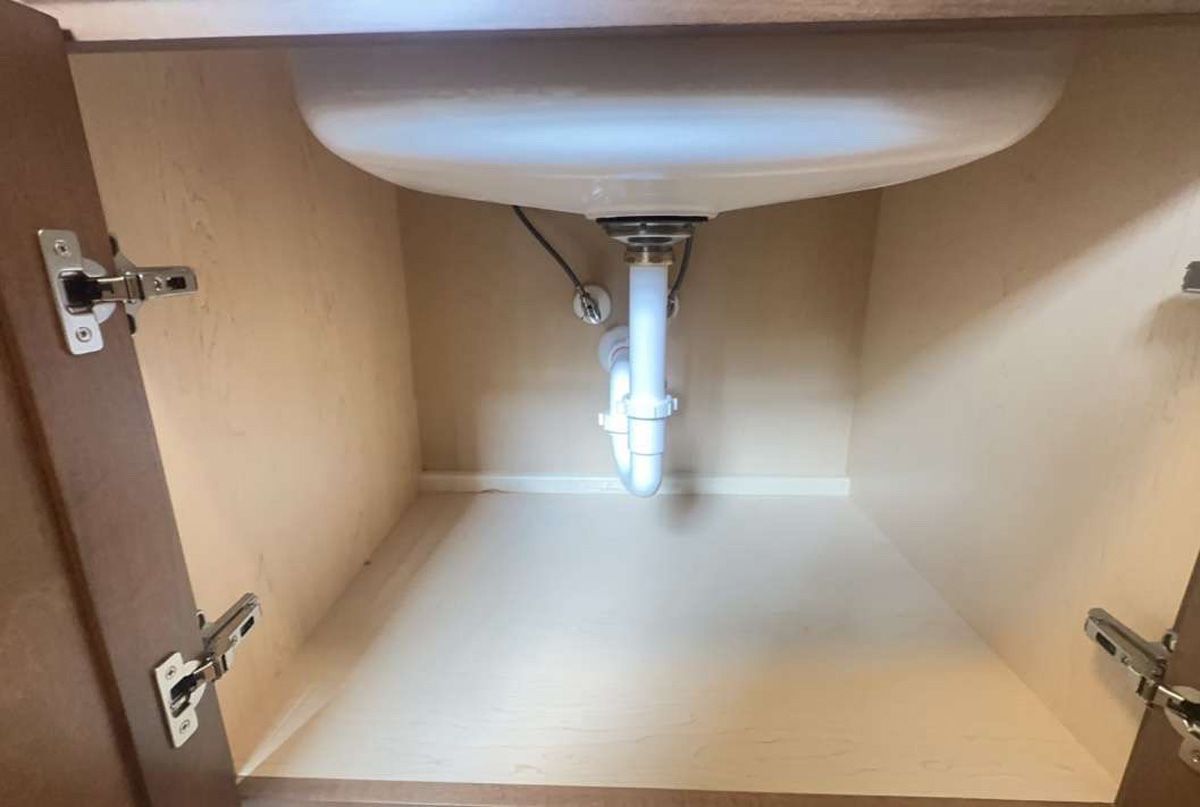 A sink is sitting under a cabinet in a bathroom.