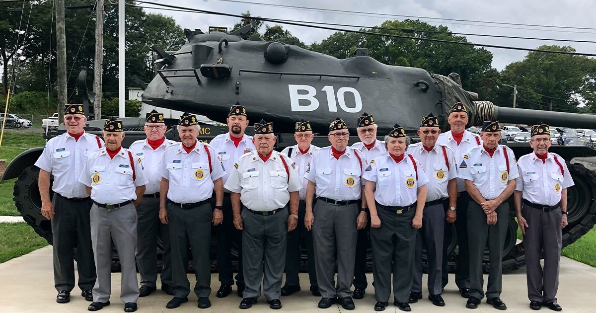 A woman is holding an american flag and a rose at a funeral.