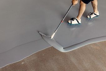 Worker applying epoxy coating to concrete floor