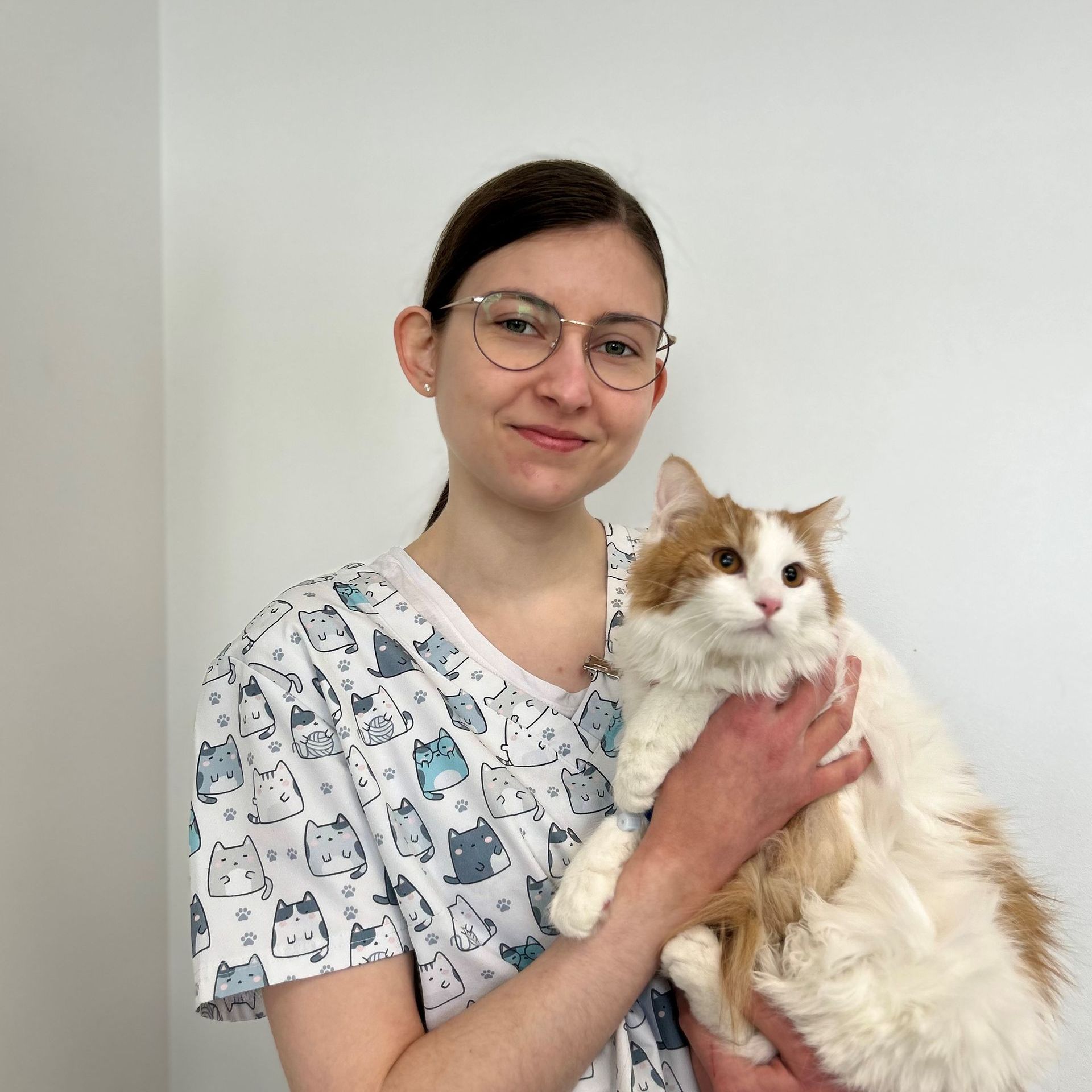 Une femme en blouse médicale tient un chat dans ses bras.