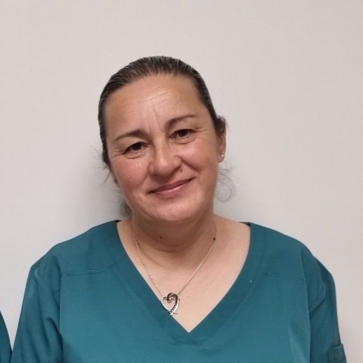 Une femme portant un haut de gommage bleu et un collier sourit à la caméra