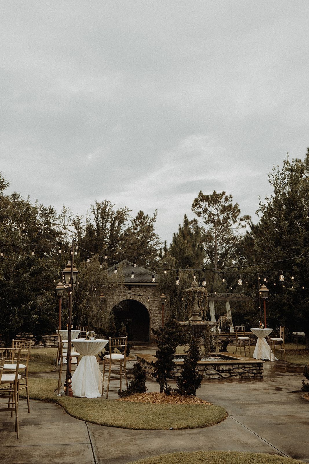 Wedding venue with stone gazebo, decorated tables, chairs, and overcast sky.