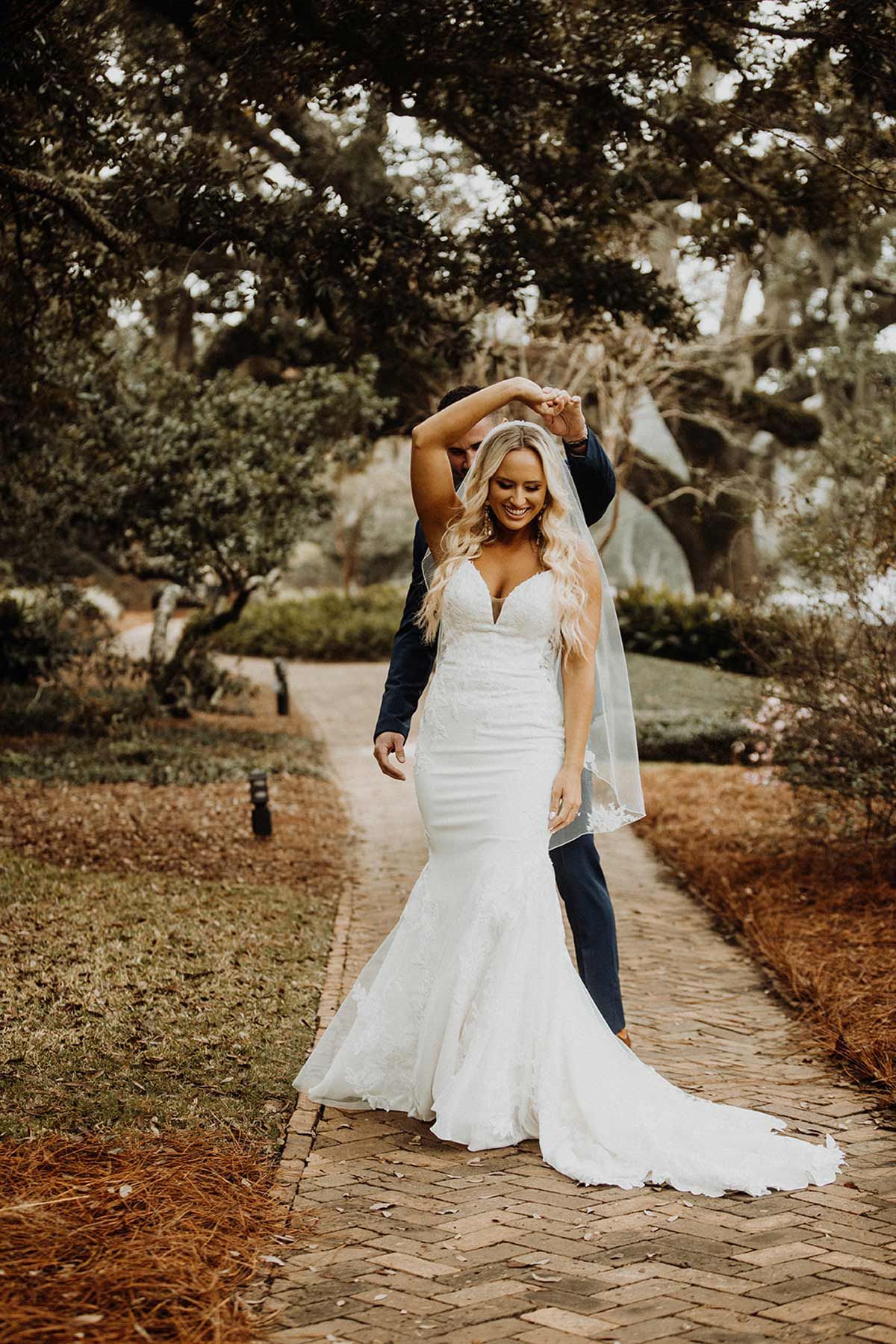 Bride and groom dancing outdoors in a garden, bride in white dress, groom in suit.