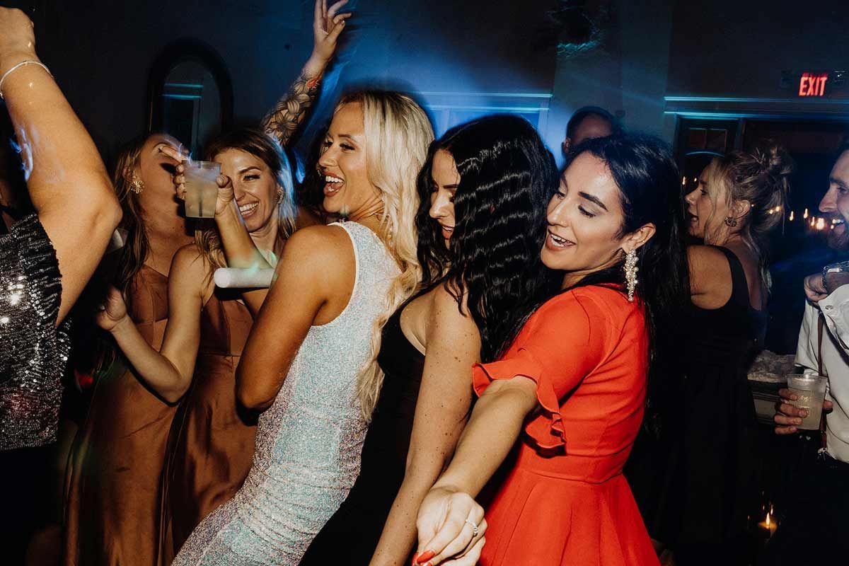 People dancing joyfully at a party, in a dimly lit room with blue and red lighting.