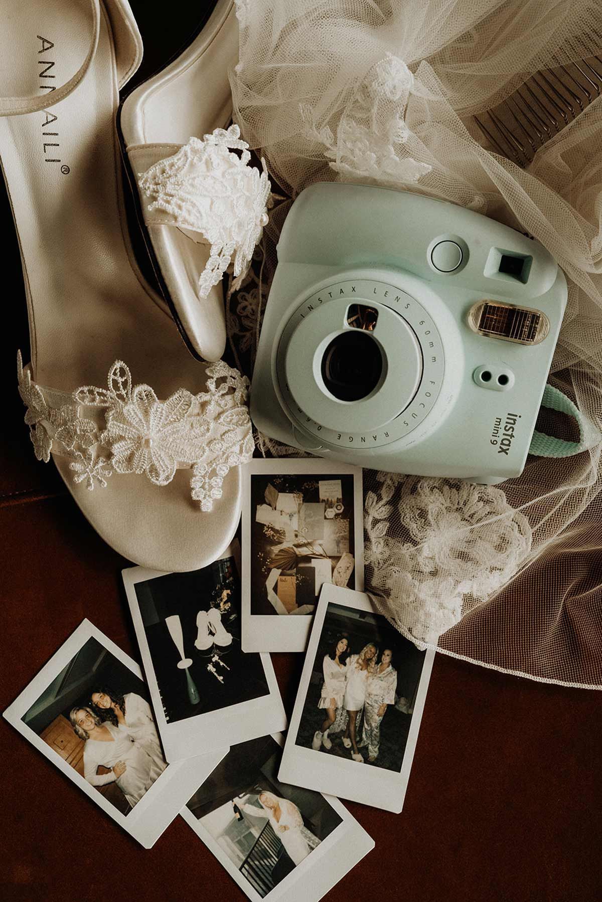 Wedding details: white lace heels, mint camera, printed photos on table.