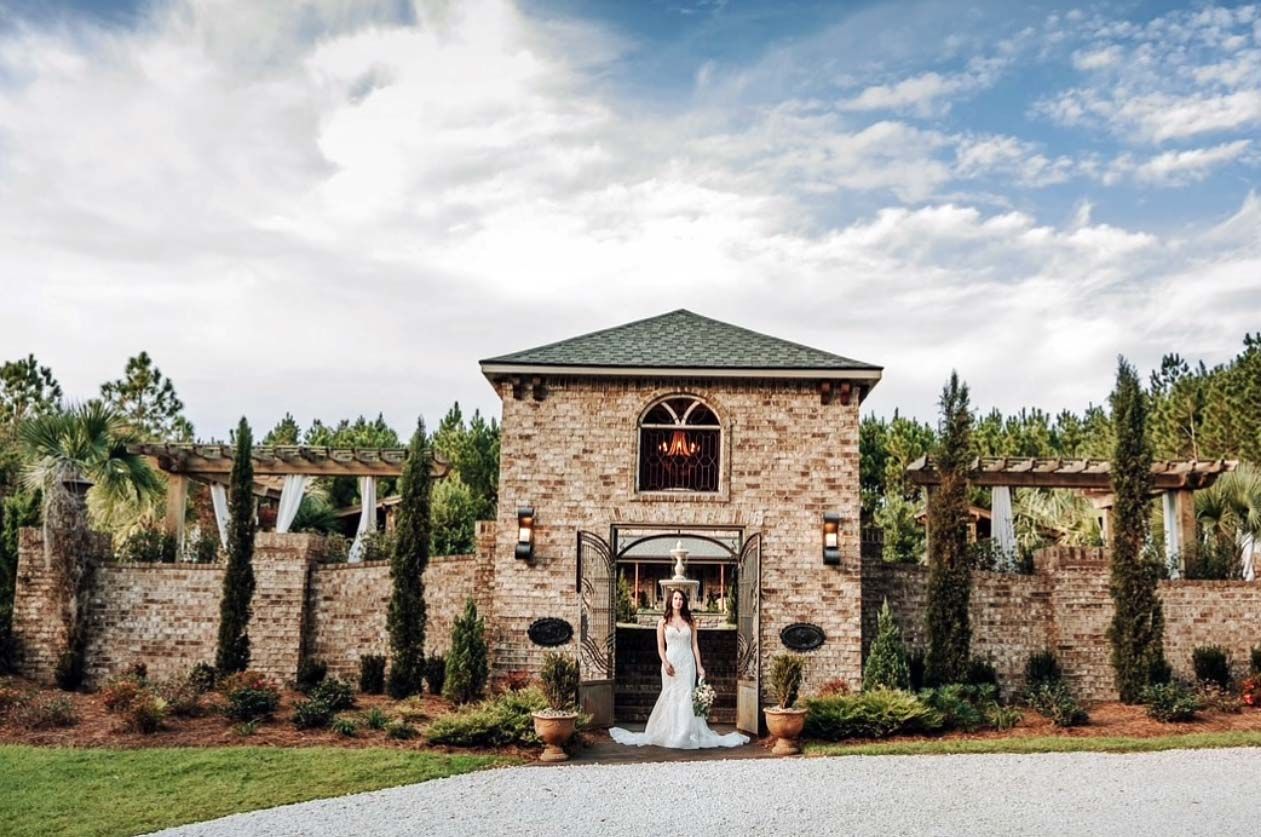 Bride in wedding dress standing in arched doorway of stone building.