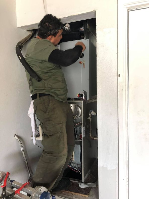 A man is working on a water heater in a room.