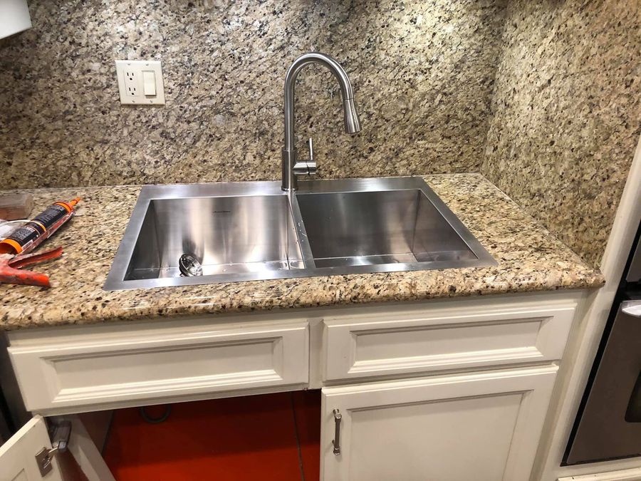 A stainless steel sink is sitting on top of a granite counter in a kitchen.