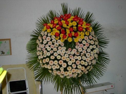 allestimento di fiori bianchi, gialli e rossi per cerimonia funebre